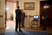 English: President Barack Obama waits with staffer Brian Mosteller and Personal Aide Reggie Love prior to his live prime time press conference in the East Room 3/24/09.