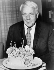Robert Frost poses with his birthday cake on his 85th birthday