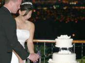 Photo of wedded American couple performing the ritual of cutting the cake together. At The Mountain Winery, Saratoga, California, US. Looking east over the Santa Clara Valley. Taken 6/26/04 by Paul Endo.