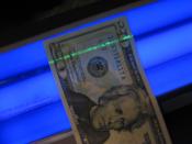 A U.S. $20 bill under a blacklight, showing the security strip glowing green.